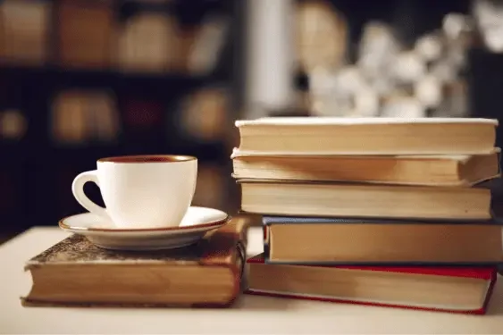 Image representing a stack of books and a coffee on a table